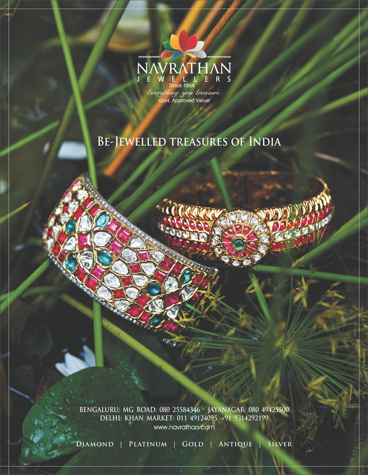 Navrathan gold bangles set with red and green gemstones among green foliage